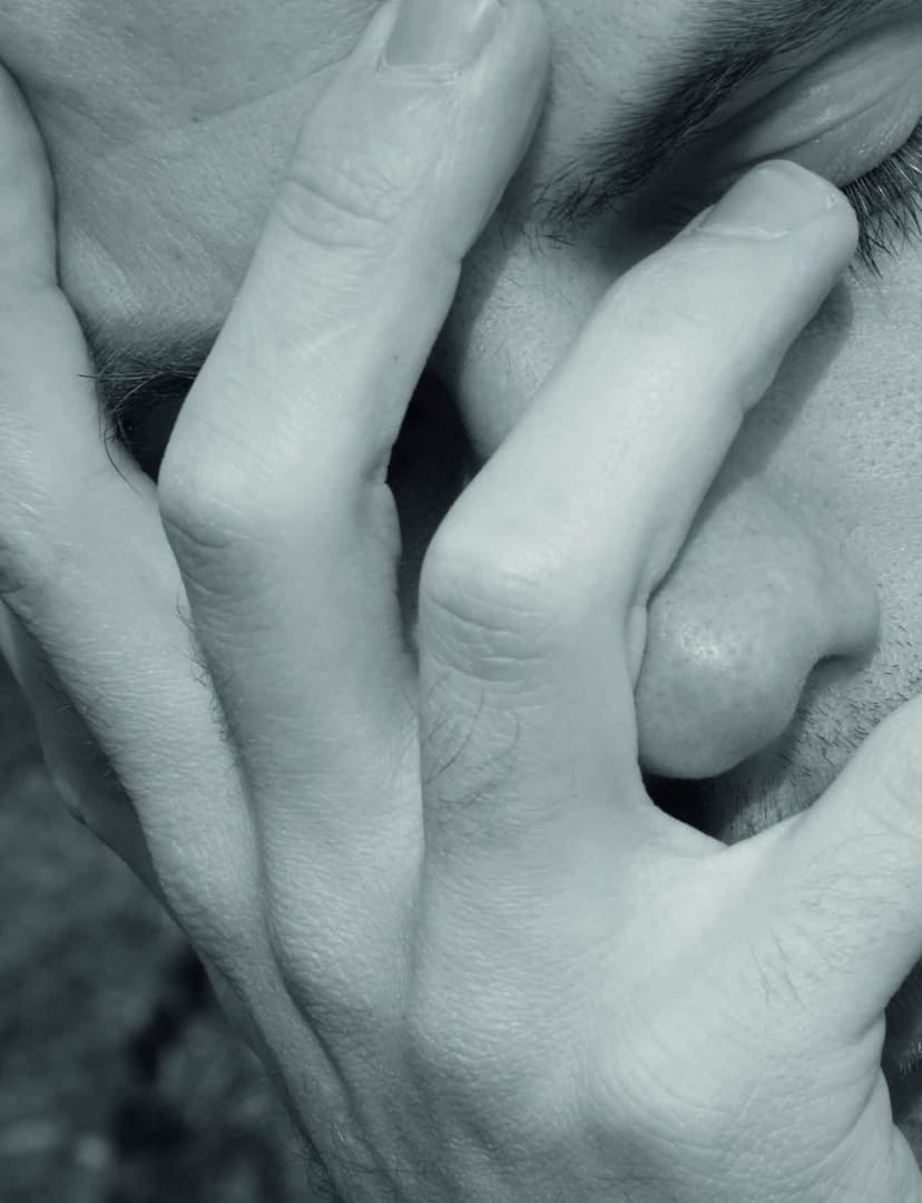 Nahaufnahme eines besorgten Gesichts, das sich mit beiden Händen die Augen verdeckt
